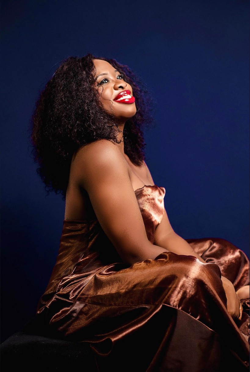 Iyabode in a brown dress against a deep blue background